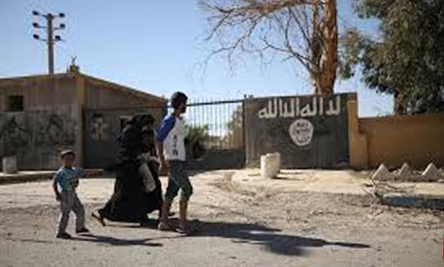 People walk past an Islamic State wall sign in the town of Tabqa, REUTERS
