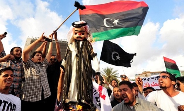 Protesters burn an effigy of Qatar`s Emir Sheikh Hamad bin Khalifa al-Thaniat as they wave the flags of Cyrenaica and Libya during a demonstration against the Muslim Brotherhood Qatar, for interfering in local politics, in Benghazi, May 10, 2013 - REUTERS