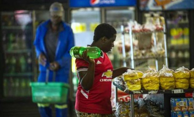 A woman holding a bottle of soft drink as she shops around at a local supermarket in the Township of Zandspruit, Greater Johannesburg, South Africa - AFP