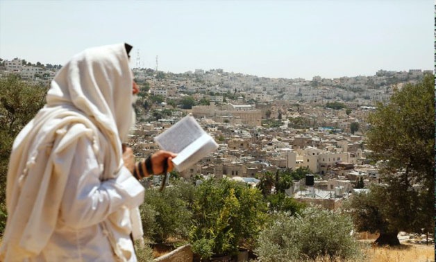 An Israeli settler stands on Palestinian land overlooking the Ibrahimi Mosque and the old city of the West Bank town of Hebron (AFP Photo/HAZEM BADER)