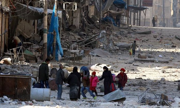 Syrians walk over rubble of damaged buildings, while carrying their belongings, as they flee clashes between government forces and rebels in Tariq al-Bab and al-Sakhour neighborhoods of eastern Aleppo towards other rebel held besieged areas of Aleppo, Syr