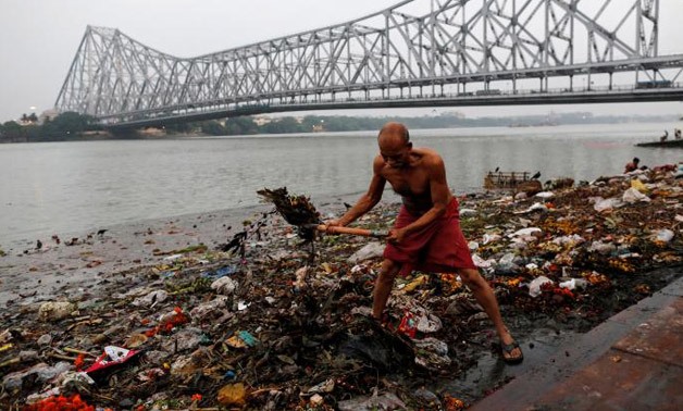 A man cleans garbage along the banks of the river Ganges in Kolkata - REUTERS/Danish Siddiqui