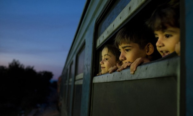 Three children look out of the window of a train, which was boarded by refugees primarily from Syria, Afghanistan and Iraq - Photo UNICEF - Ashley Gilbertson