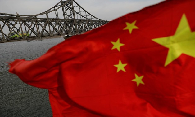 FILE PHOTO: A Chinese flag is seen in front of the Friendship bridge over the Yalu River connecting the North Korean town of Sinuiju and Dandong in China's Liaoning Province, April 1, 2017.
