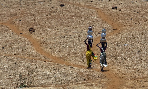 Indian women walk home after collecting drinking water from a well at Mengal Pada in Thane district in Maharashtra state, India, after a heatwave and severe drought conditions struck the region.