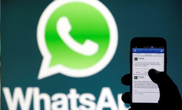 A WhatsApp logo is seen behind a phone that is logged on to Facebook in the central Bosnian town of Zenica, February 20, 2014.