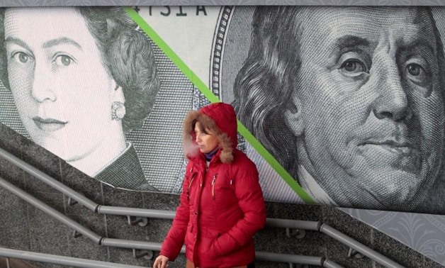 A woman smokes near an outdoor ad with an image of the British pound and U.S. dollar bank notes in central Kiev November 19, 2012, Reuters
