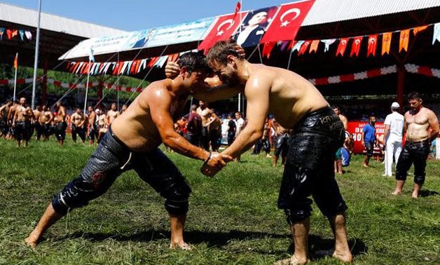 Wrestlers warm up before competing in the annual Kirkpinar oil wrestling tournament at the Sarayici arena in Edirne, Turkey July 14, 2017-Murad Sezer