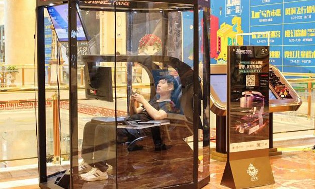 A man playing video games in a booth at a shopping mall in Shanghai. China has the solution for weary men in shopping malls everywhere: so-called husband rest booths. - AFP