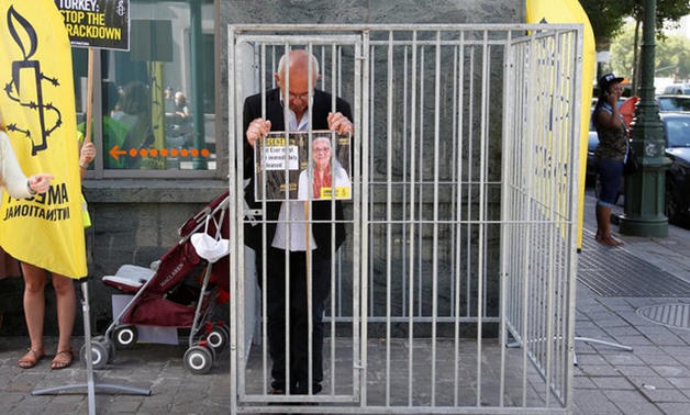 Amnesty International Belgium's Director Philippe Hensmans poses in a cage in front of the Turkish embassy in Brussels to protest against the detention of his Turkish counterpart Idil Eser - Reuters