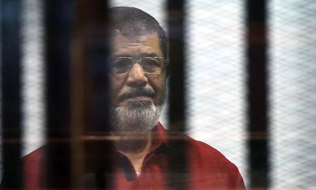 Egypt’s ousted President Mohamed Morsi, wearing a red uniform, stands behind bars during his trial in Cairo, Egypt, June 21, 2015. (© AFP)