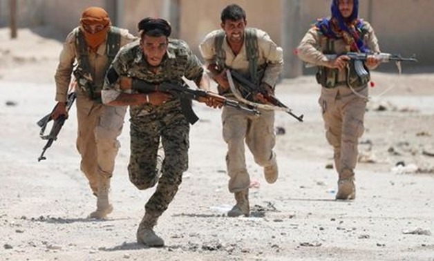 Kurdish fighters from the People's Protection Units (YPG) run across a street in Raqqa, Syria July 3, 2017.
