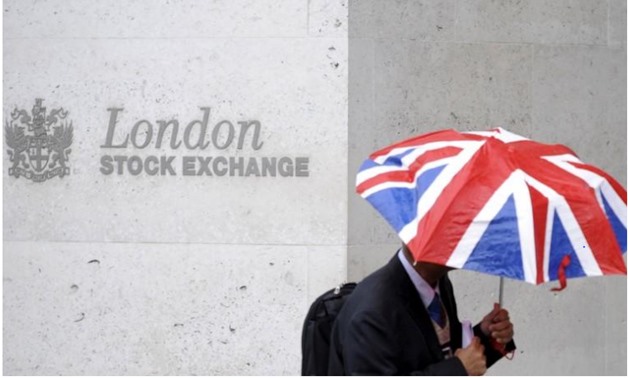 A worker shelters from the rain under a Union Flag umbrella as he passes the London Stock Exchange - Reuters/Toby Melville