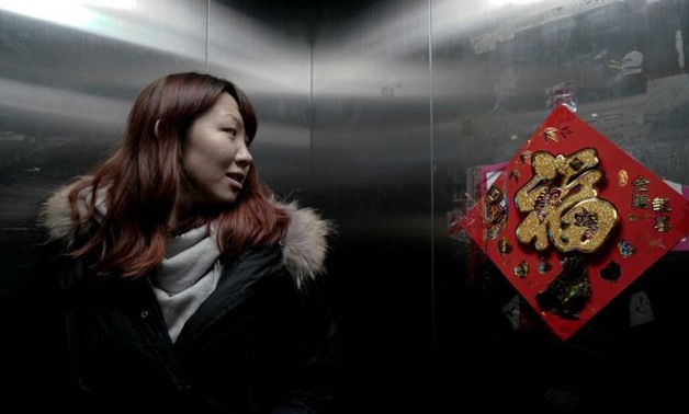 Zhao Yuqing looks at a Chinese character "Fu", which means good fortune, on a poster in the elevator of her apartment, in Beijing, China, January 25, 2017. - Reuters