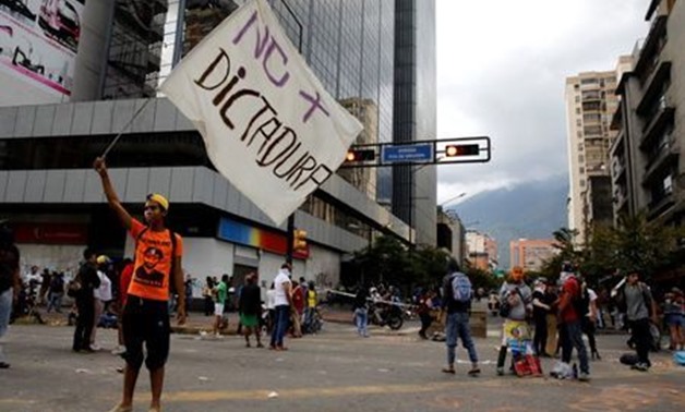 FILE PHOTO: A demonstrator holds up a banner that reads "No more dictatorship" at a rally against Venezuelan President Nicolas Maduro's government in Caracas, Venezuela, July 18, 2017. REUTERS/Carlos Garcia Rawlins
