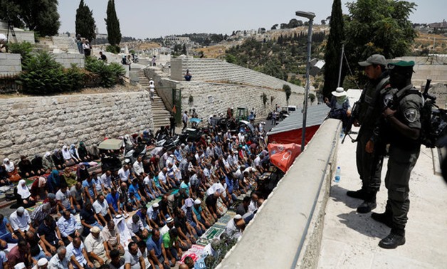 Israeli border police officers stand guard as Palestinians pray at Lions' Gate, the entrance to Jerusalem's Old City, in protest over Israel's new security measures at the compound housing al-Aqsa mosque, known to Muslims as Noble Sanctuary and to Jews as