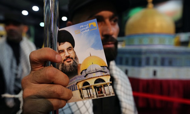 A Hezbollah member holds a placard depicting Lebanon's Hezbollah leader Sayyed Hassan Nasrallah and Dome of the Rock during a rally marking Al-Quds day in Beirut's southern suburbs, Lebanon June 23, 2017. REUTERS/Aziz Taher
