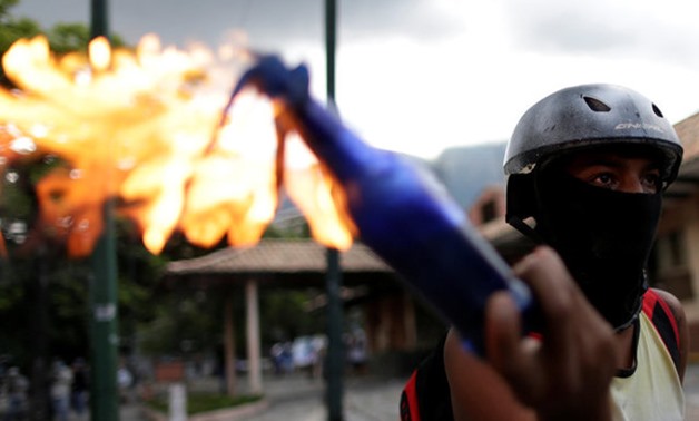 A demonstrator holds a petrol bomb while clashing with riot security forces during a rally against Venezuela's President Nicolas Maduro's government in Caracas - Reuters