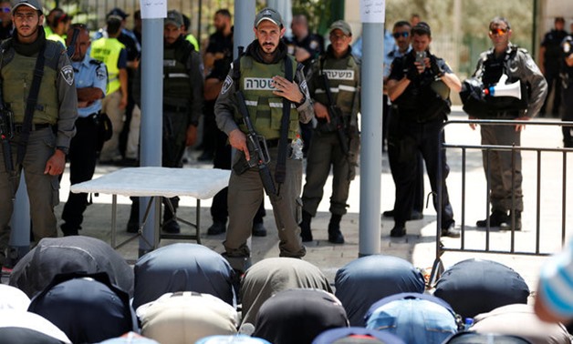 FILE PHOTO: Palestinians pray in front of Israeli policemen and newly installed metal detectors at an entrance to the compound known to Muslims as Noble Sanctuary and to Jews as Temple Mount in Jerusalem's Old City July 16, 2017. REUTERS/Ronen Zvulun/File