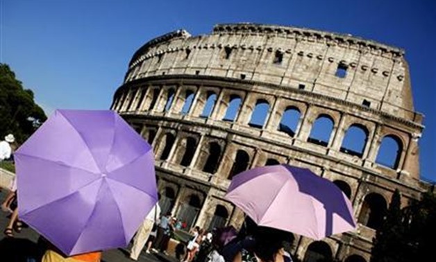 Tourists use umbrellas to shade themselves from the sun as they visit Rome's ancient Colosseum during a hot summer day in Rome July 21, 2010 - Reuters