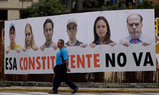 A man walks past a banner in Caracas - Reuters