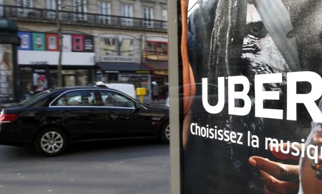 FILE PHOTO: A taxi passes by an advertisement for the Uber car and ride-sharing service displayed on a bus stop in Paris, France, in this March 11, 2016 file photo.
Charles Platiau