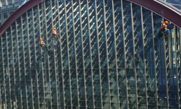 Workers clean windows over looking Docklands Light Railway - Reuters