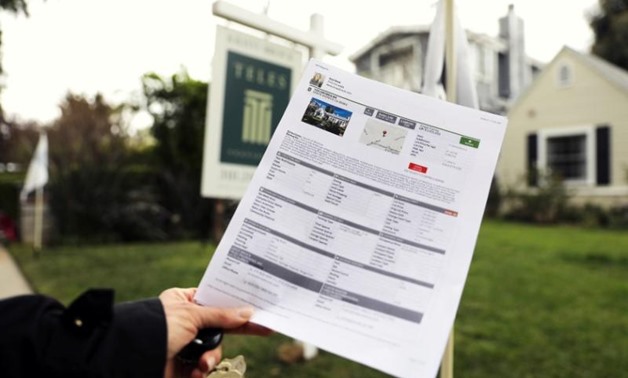 A woman holds a piece of paper advertising a home for sale in Santa Monica, California, U.S., March 21, 2017, REUTERS