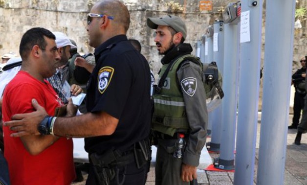  An Israeli police officer checks the identity of a Palestinian man next to newly installed metal detectors at Al-Aqsa Mosque - Reuters photo