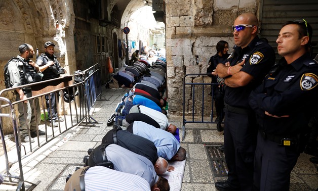 Palestinian men pray as Israeli security forces secure outside the compound known to Muslims as Noble Sanctuary and to Jews as Temple Mount, in Jerusalem's Old City July 26, 2017. 