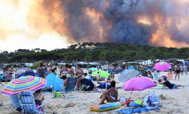 © AFP | People watch from the beach as smoke billows into the sky over Bormes-les-Mimosas
