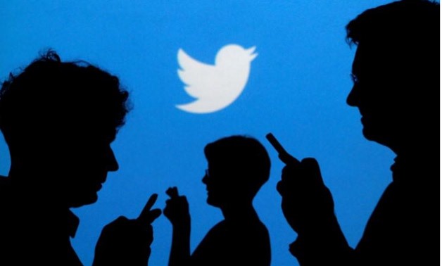People holding mobile phones are silhouetted against a backdrop projected with the Twitter logo in this illustration picture taken - Reuters
