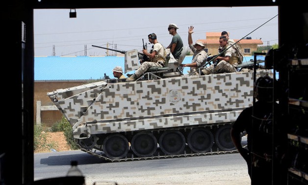 A man watches Lebanese army soldiers ride on a military tank in Labwe, at the entrance of the border town of Arsal -  REUTERS