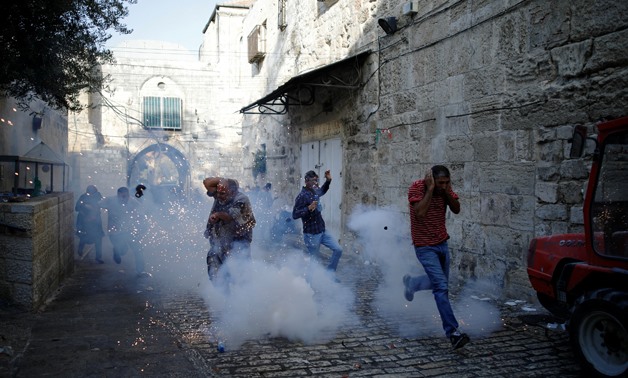 Palestinians react as a stun grenade explodes in a street at Jerusalem's Old city outside Al-Aqsa compound on July 27, 20- Reuters