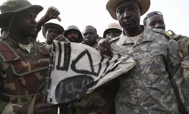 Nigerien soldiers hold up a Boko Haram flag they had seized in the recently retaken town of Damasak, Nigeria, March 18, 2015, REUTERS