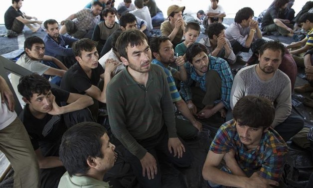Suspected Uighurs from China's troubled far-western region of Xinjiang, sit inside a temporary shelter after they were detained at the immigration regional headquarters near the Thailand-Malaysia border in Hat Yai, Songkla March 14, 2014 - REUTERS