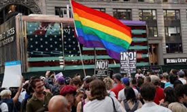 A rainbow flag flies as people protest President Donald Trump's announcement that he plans to reinstate a ban on transgender individuals from serving in any capacity in the U.S. military, in Times Square, in New York City, New York.
