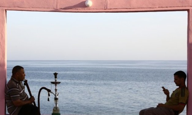 © AFP/File | A massive Saudi tourism project will cover more than 180 kilometres of coastline stretching from Umm Lajj to Al-Wajh, where two men are seen here at a cafe overlooking the Red Sea
