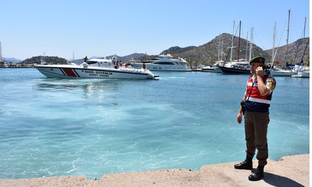A Turkish gendarme, with a Coast Guard boat in the background, stands on the shore in the resort town of Marmaris in Mugla province, Turkey, August 2, 2017. REUTERS