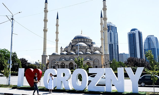 Young people take a photo in front of the Heart of Chechnya – Akhmad Kadyrov Mosque and large letters reading ‘I love Grozny’ in central Grozny - AFP