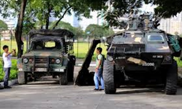 A man use a mobile phone to take pictures of his friend beside an Armoured Personnel Carrier (APC) parked near the venue of the 50th ASEAN Foreign Ministers meeting in Pasay city, metro Manila, Philippines August 4, 2017.
