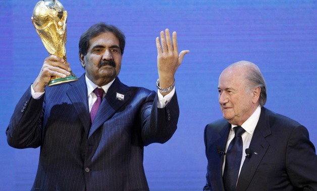 Qatar's Emir Sheikh Hamad bin Khalifa al Thani (L) holds up a copy of the World Cup he received from FIFA President Sepp Blatter (R) after the announcement that Qatar is going to be host nation for the FIFA World Cup 2022, in Zurich December 2, 2010 - Reu