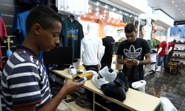 © AFP / by Ibrahim Abdallah | A young Libyan uses a mobile phone app to pay at a Benghazi store that accepts electronic payment systems
