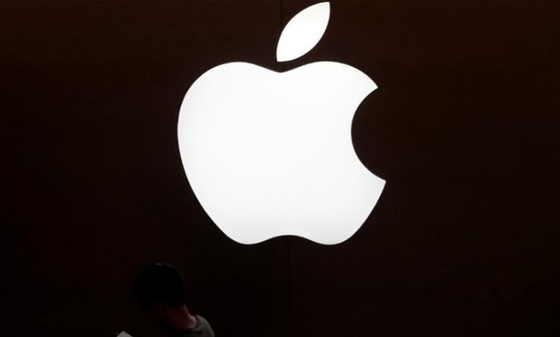 A man looks at the screen of his mobile phone in front of an Apple logo outside its store in Shanghai - Reuters