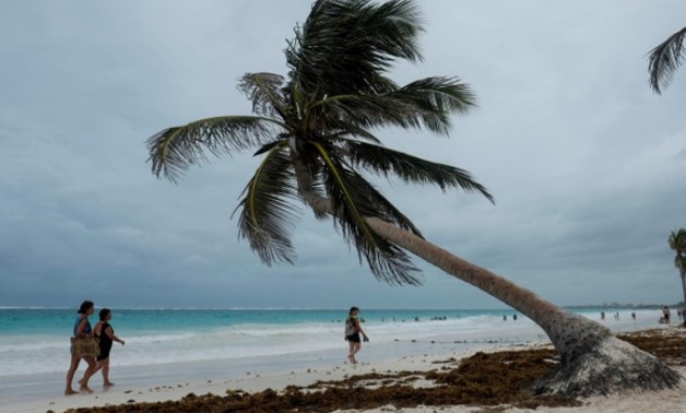 Tourists walk along a beach with heavy clouds caused by the proximity of tropical storm Franklin that is near the coast of Quintana Roo, in Tulum