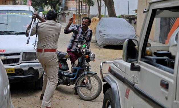 Police raises his baton at a man who defied a curfew in Bengaluru, following violent protests after India's Supreme Court ordered Karnataka state 