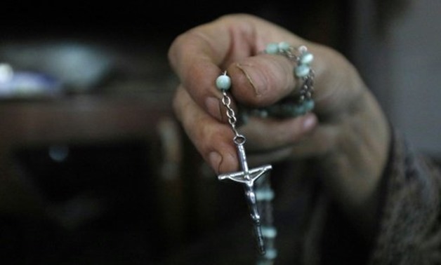  A member of an Armenian Christian family who fled Raqa holds a rosary in Jazra, a suburb of the northern Syrian city, on August 8, 2017- AFP