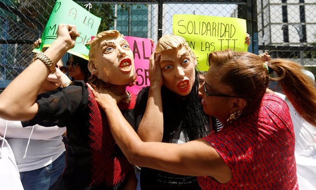 Members of the LGBT community wear a mask depicting U.S. President Donald Trump as they gesture in a protest against Trump's sudden decision to ban transgender personnel from serving in the military, nearby the U.S embassy in Mexico City - REUTERS