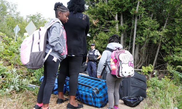 A family who identified themselves as from Haiti are confronted by a RCMP officer as they try to enter into Canada from Roxham Road in Champlain New York - REUTERS