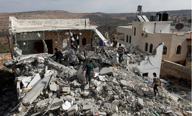 People walk through the rubble of the house of a Palestinian assailant after it was demolished by Israeli troops in the West Bank village of Deir Abu Mashal, near Ramallah - REUTERS